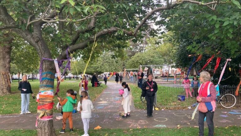 Trees dressed with materials and children chalking the pavement