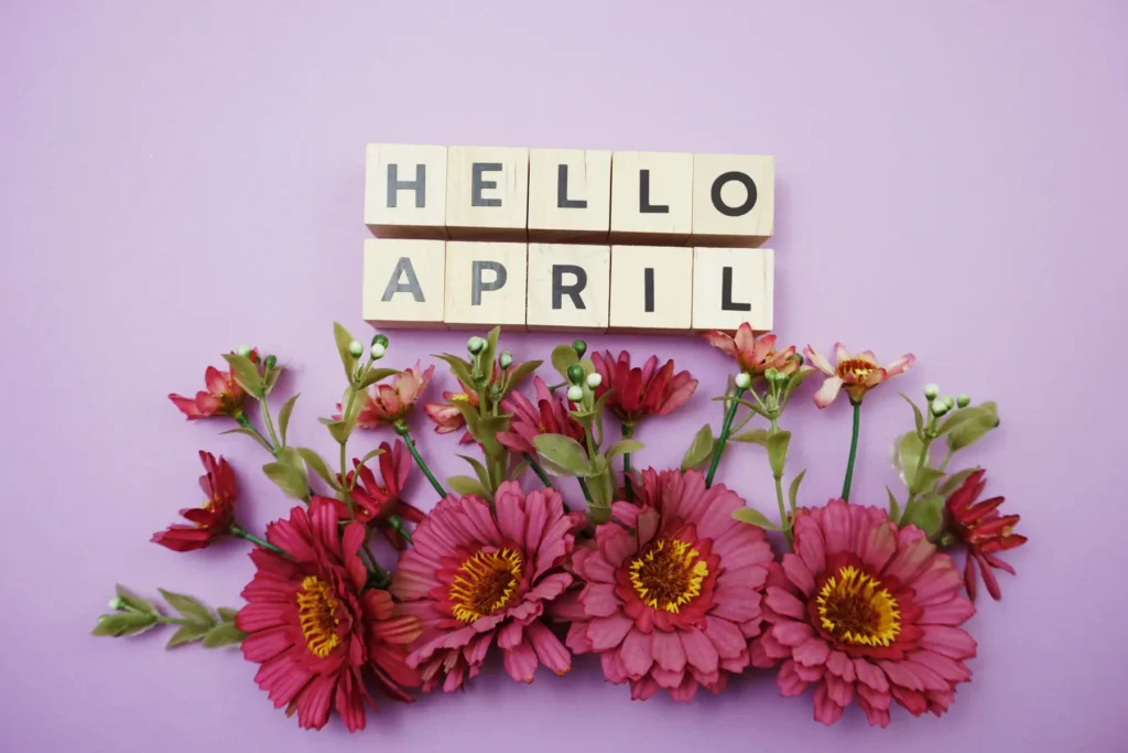 Hello April spelt out in Scrabble tiles above cut flowers.